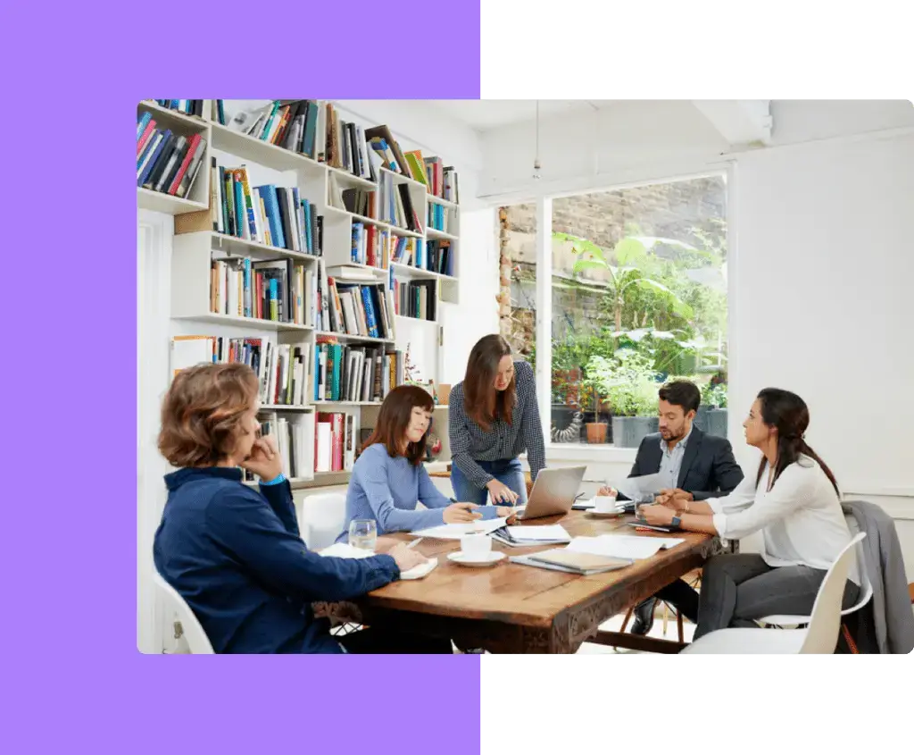 A publishing team in discussion around a table, representing the collaborative and supportive services provided by eMagazines.
