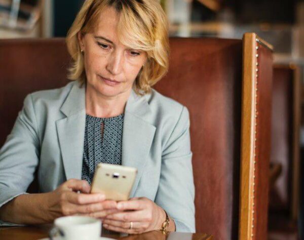 woman sitting at booth with coffee looking at her phone