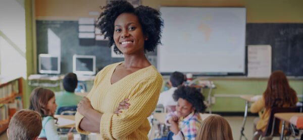 female teacher proudly stands in from of classroom of children
